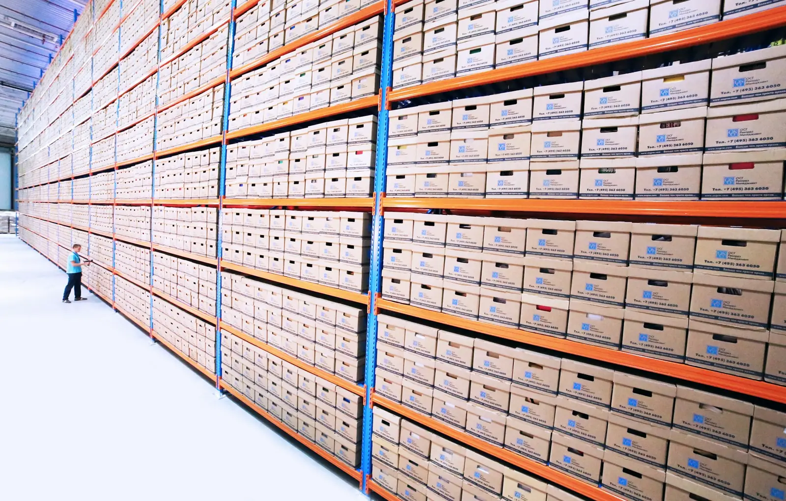 Hohe Regalwand voller beschrifteter Archivkartons in einer hellen Lagerhalle, Symbolbild